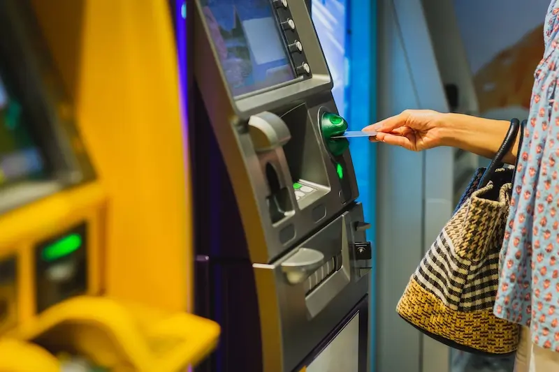 Woman hand insert a credit card into an ATM machine.